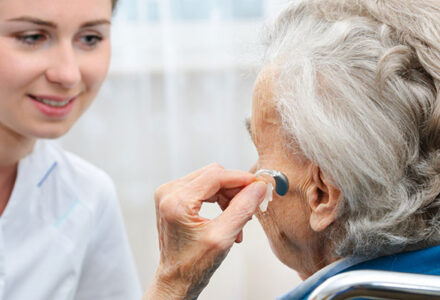 An elderly woman is fitted for a hearing aid