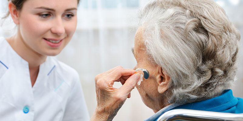 An elderly woman is fitted for a hearing aid